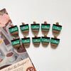 A set of green and brown coffee bean fridge magnets displayed on a piece of paper.