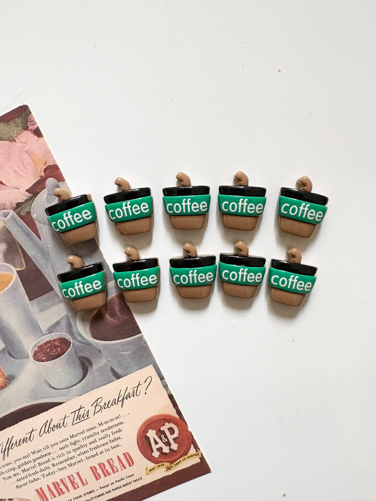 A set of green and brown coffee bean fridge magnets displayed on a piece of paper.