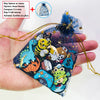 Une main tient une pochette transparente remplie de charms de lettres pour Crocs, avec divers designs d'animaux et de personn