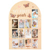 A wooden milestone board featuring photos and markers for a baby's first year, showing milestones from newborn to twelve mont