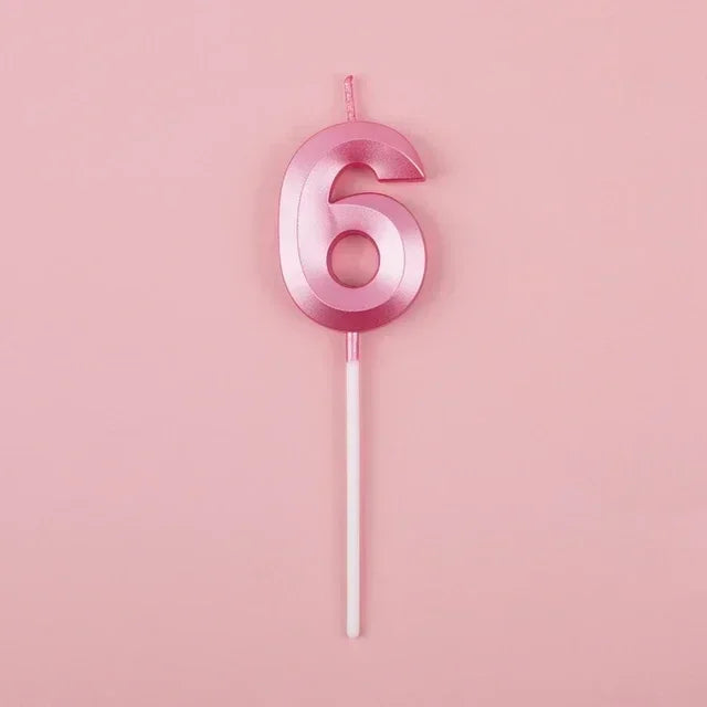 A pink number six candle on a stick against a light pink background.