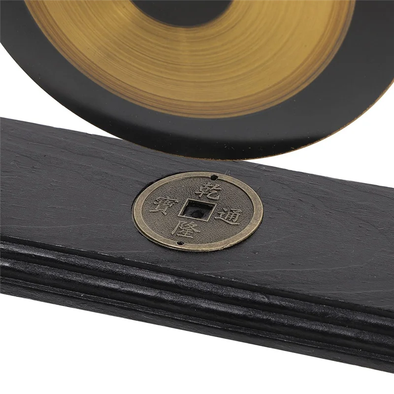 A brass Feng Shui gong decor set featuring a circular gong mounted on a black wooden plaque.