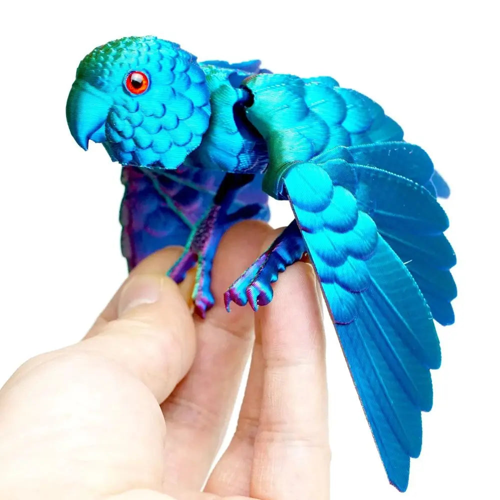 A hand holds an articulated 3D printed parrot figurine with vibrant blue wings.