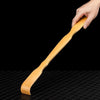 A hand holds a light brown bamboo back scratcher with a roller massager against a black background.