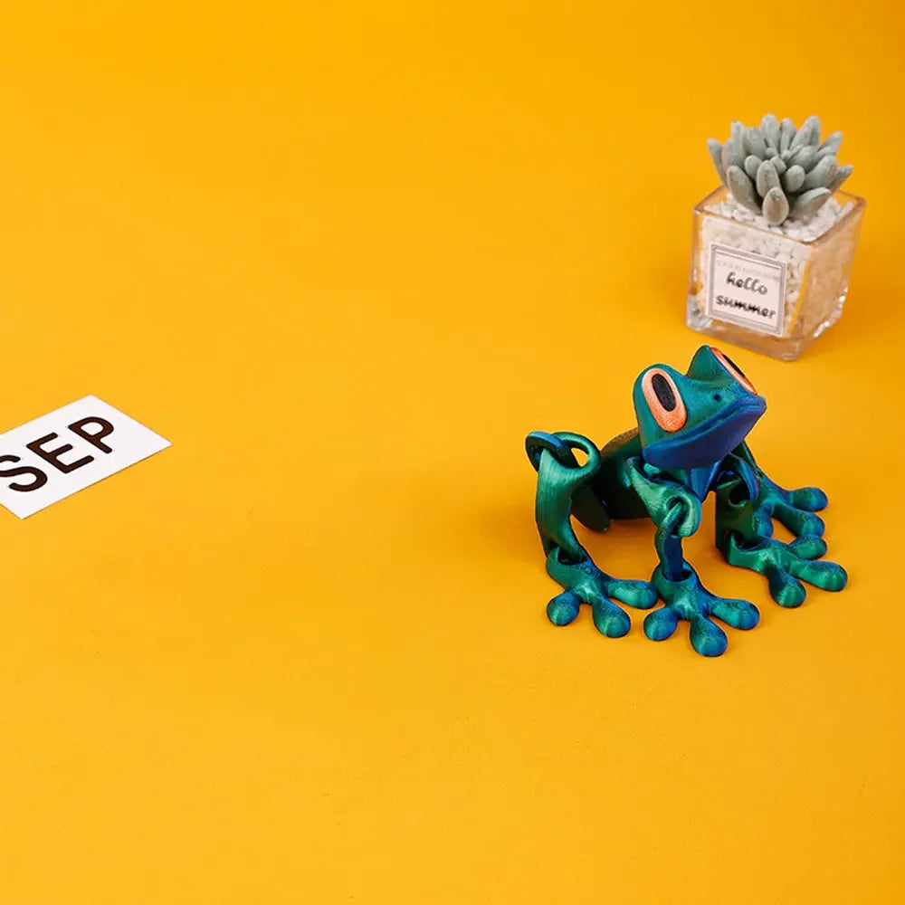 A vibrant green tree frog ornament sits next to a small potted succulent on an orange background.