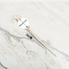 A replica metal magic wand with a wooden shaft and a circular metal core displayed on a white marble surface.