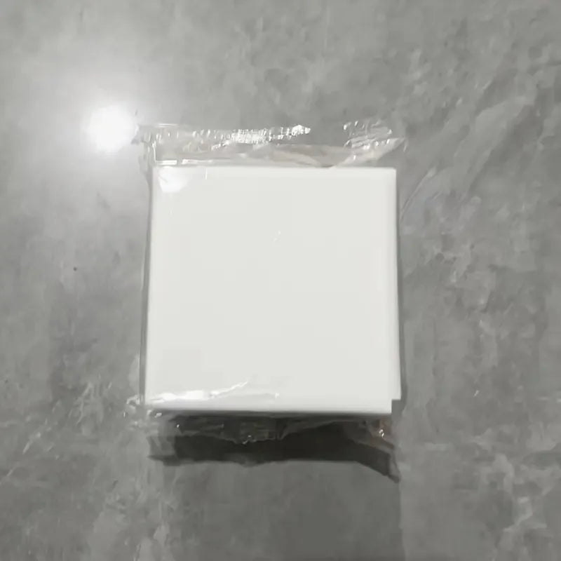 A white square storage holder for a scale with a self-adhesive mount, packaged in clear plastic.