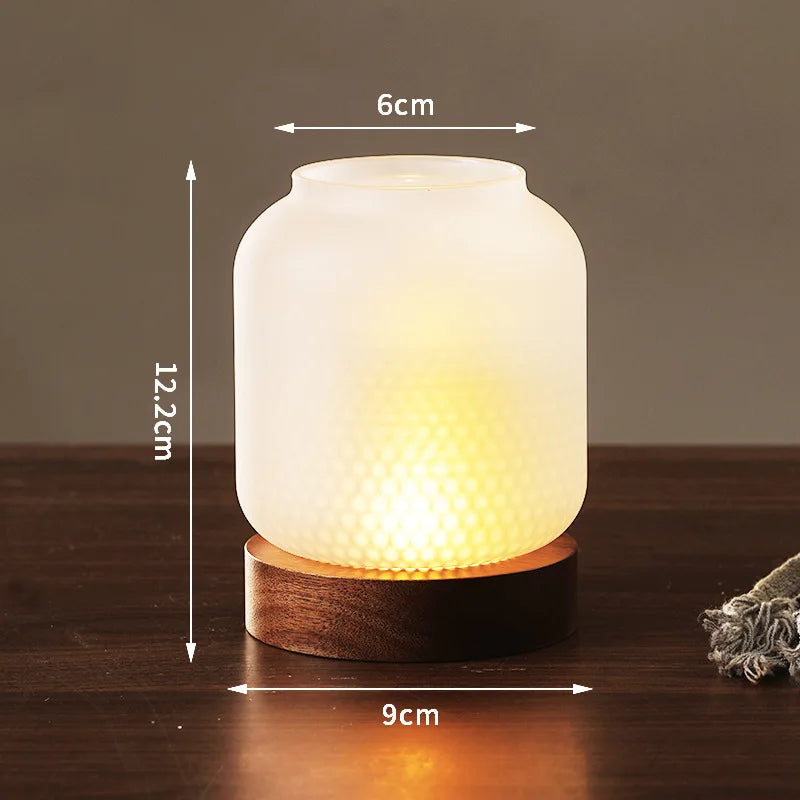 A white glass lantern with a warm glow sits on a wooden base.