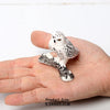 A small white owl figurine resting on a human hand.