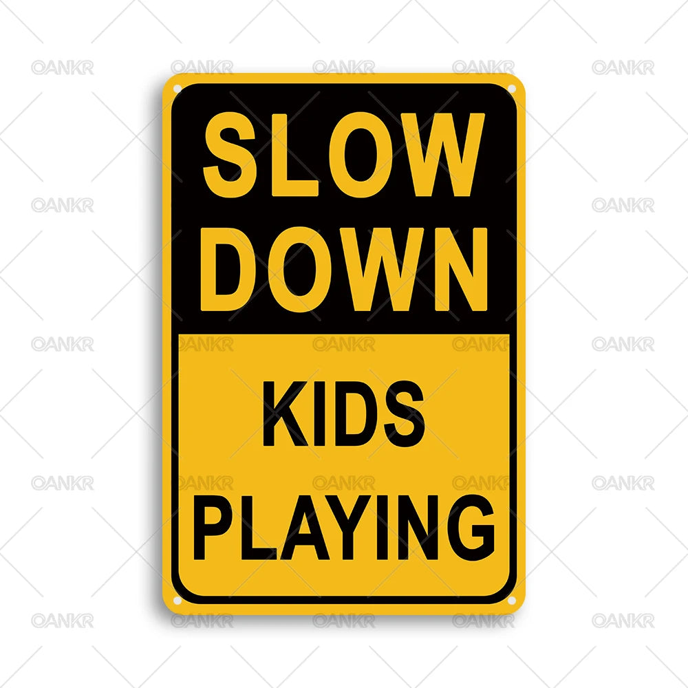 A yellow rectangular sign with black text that reads SLOW DOWN KIDS PLAYING