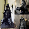 A dark resin statue of a goddess with horns and a crown, standing over two wolf figures.