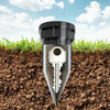 A silver key shape is embedded in dark soil with green grass surrounding it.