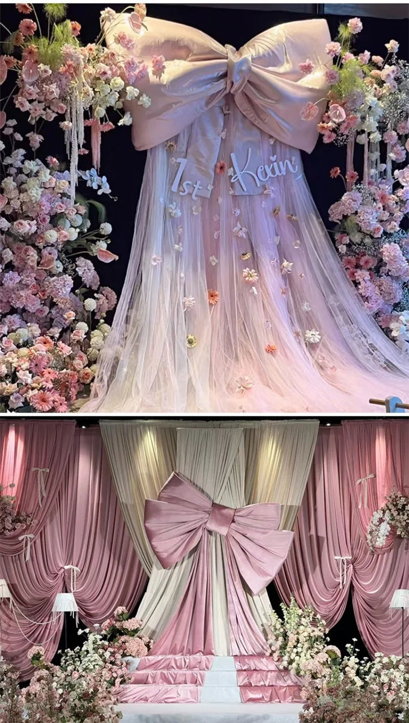 A pink satin bow with a long tulle drape is displayed as event decor, featuring floral accents.