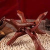 A vintage wooden tripod stand for displaying an abalone shell or crystal ball on a woven mat.