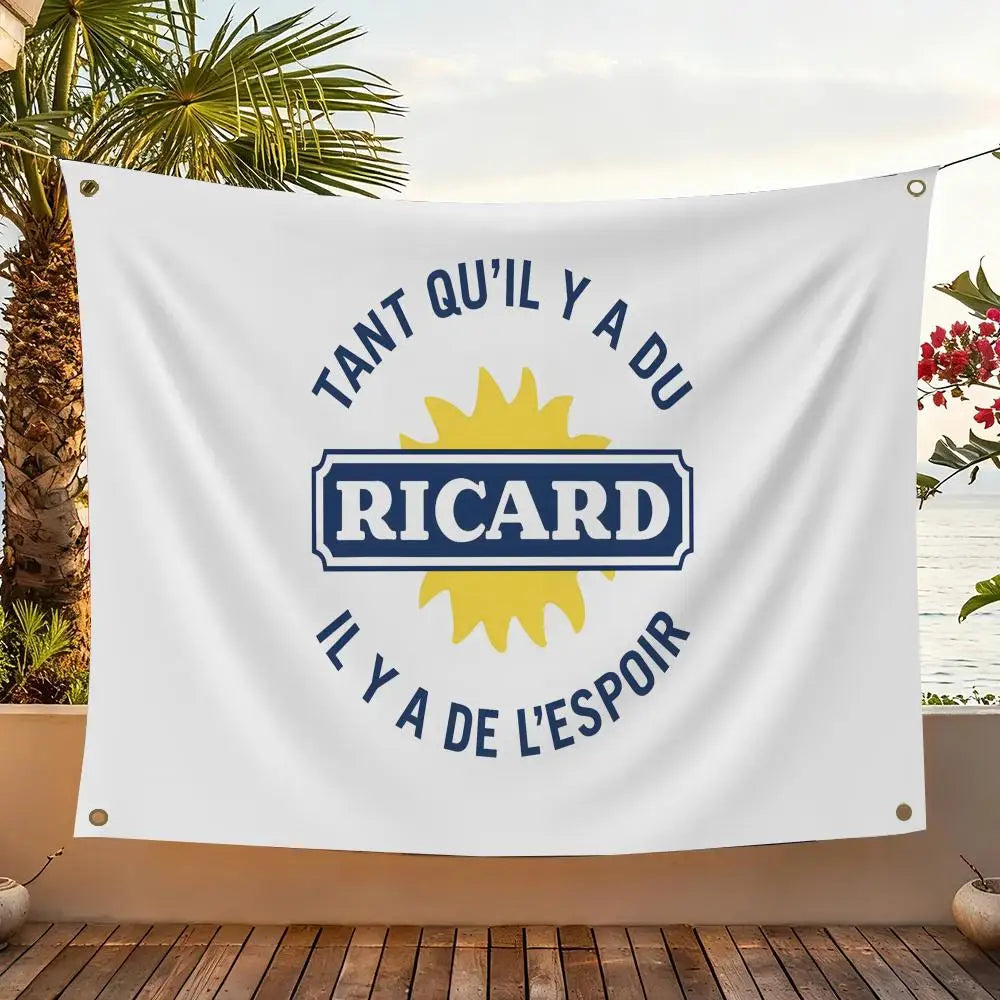 A white flag featuring blue text and a yellow sun graphic with the name RICARD and surrounding French phrases.