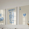 Three framed art prints featuring lucky hearts and the text I love you on a light gray wall.