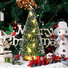 An LED mini Christmas tree decorated with a snow effect, surrounded by festive holiday decorations.