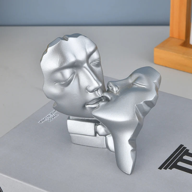 Silver resin sculpture of an abstract kissing couple with smooth, stylized features.