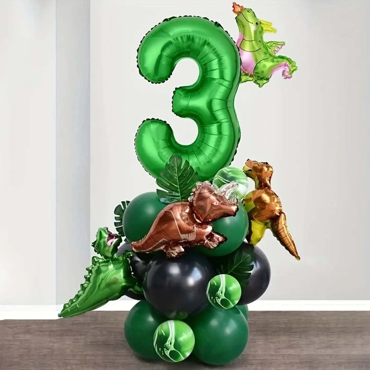 A green balloon set shaped like the number three and various dinosaur-themed balloons for a birthday party.
