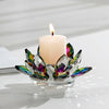 A crystal lotus tealight candle holder with iridescent glass petals and a white candle on a clear base.