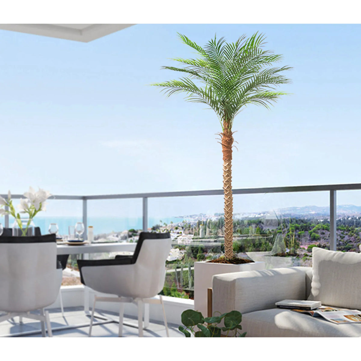 Artificial golden palm tree in a white planter set against a blue sky and ocean view