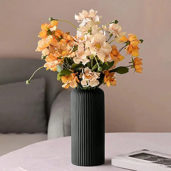 A bouquet of orange and cream flowers in a ribbed black ceramic-look vase.