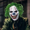 A person wearing a full-face latex mask resembling a clown with green hair and white face paint.