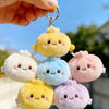 A collection of five pastel yellow, blue, pink, and purple plush butter dumpling squishy keychains being held by a hand again