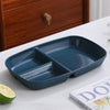 A dark blue 3-compartment portion control plate is shown on a white surface next to a lime.