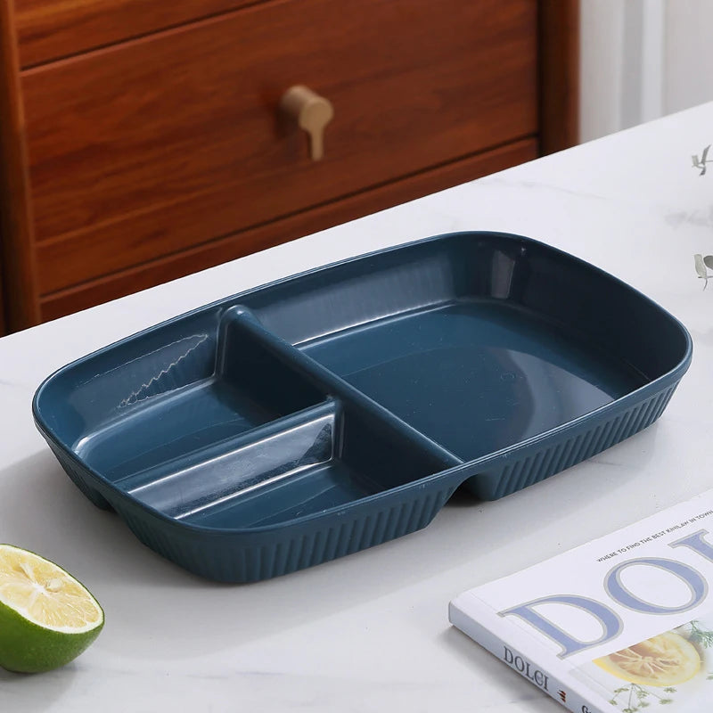A dark blue 3-compartment portion control plate is shown on a white surface next to a lime.