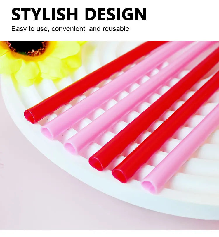 A collection of heart-shaped pink and red disposable straws are arranged on a white surface.