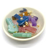 A collection of natural crystal pendants and charms in various colors like blue purple green and pink resting in a white bowl