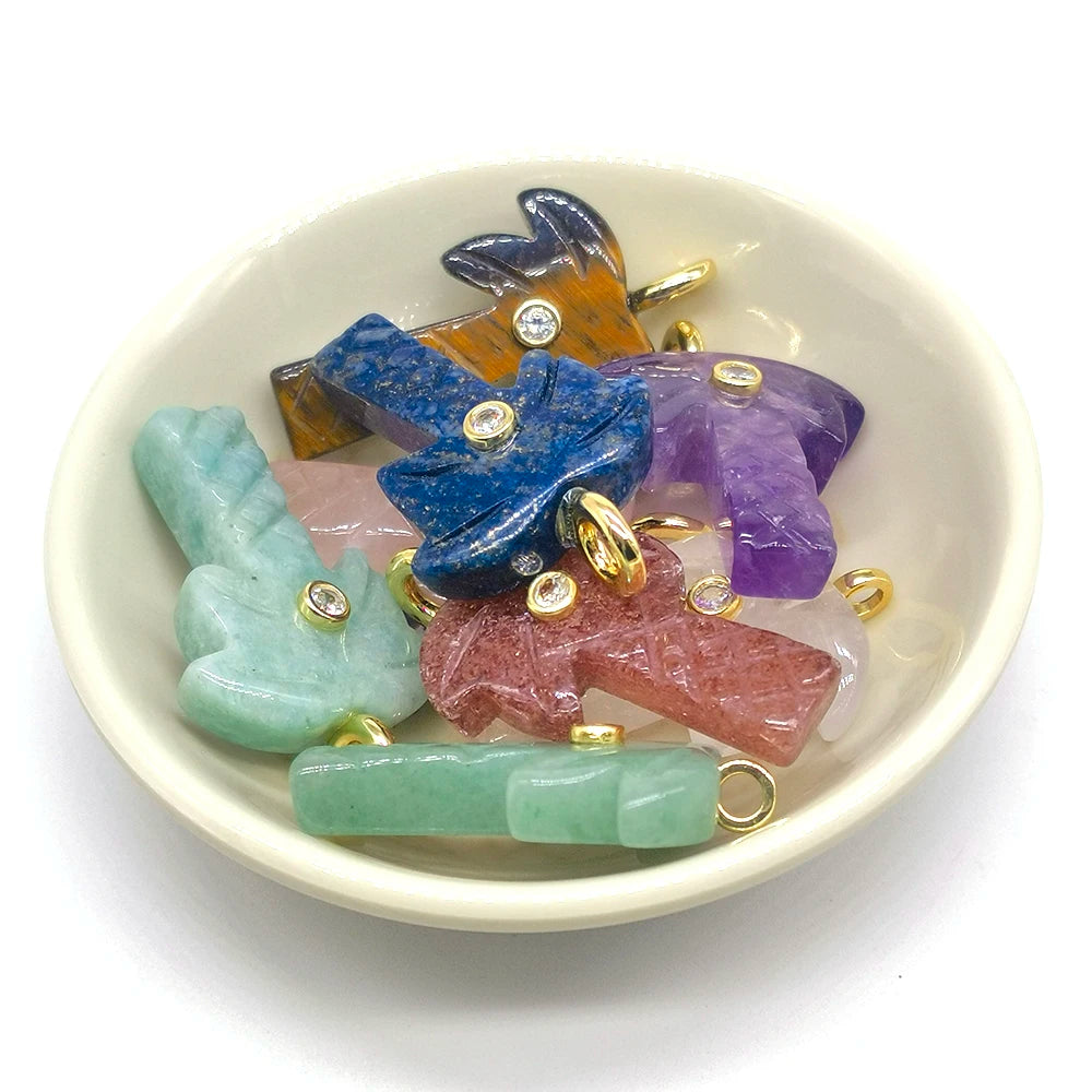 A collection of natural crystal pendants and charms in various colors like blue purple green and pink resting in a white bowl