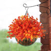 Panier suspendu rempli de fleurs artificielles d'automne orange et rouge.