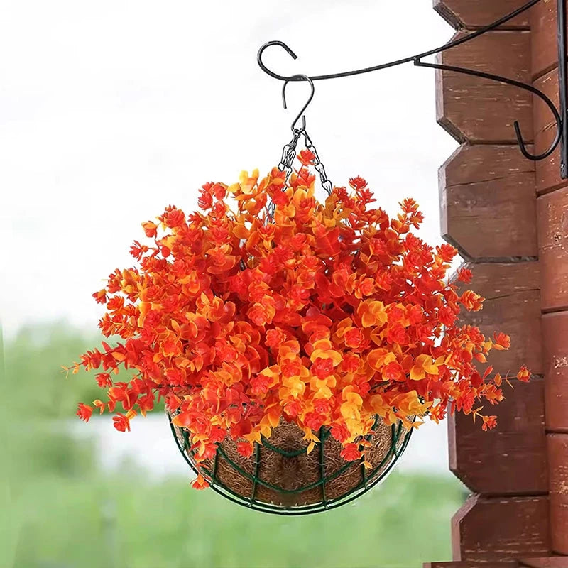 Panier suspendu rempli de fleurs artificielles d'automne orange et rouge.