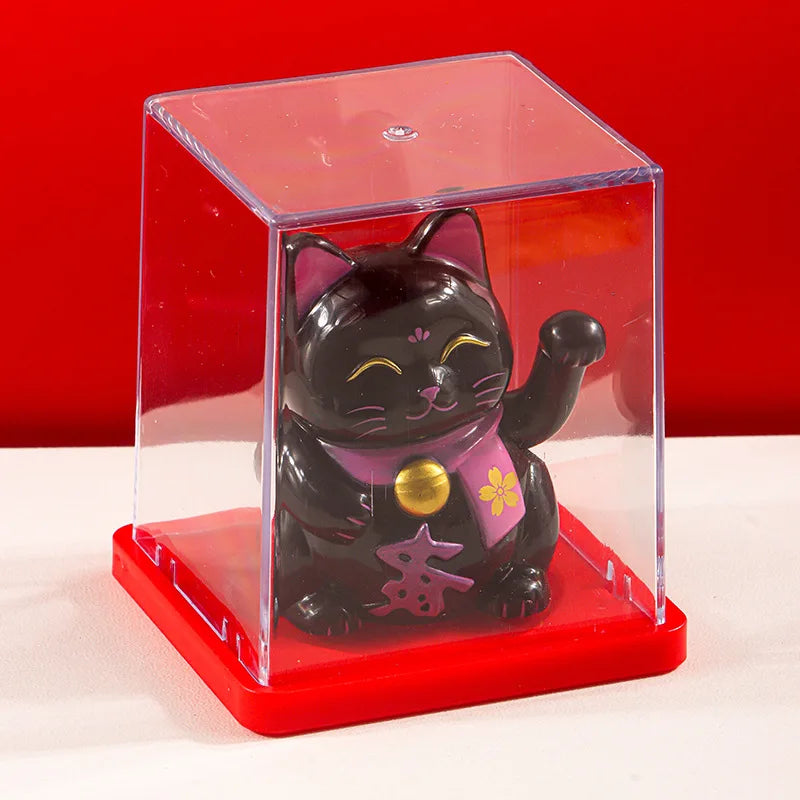 A black cat figurine with pink accents is displayed inside a clear acrylic box on a red base.