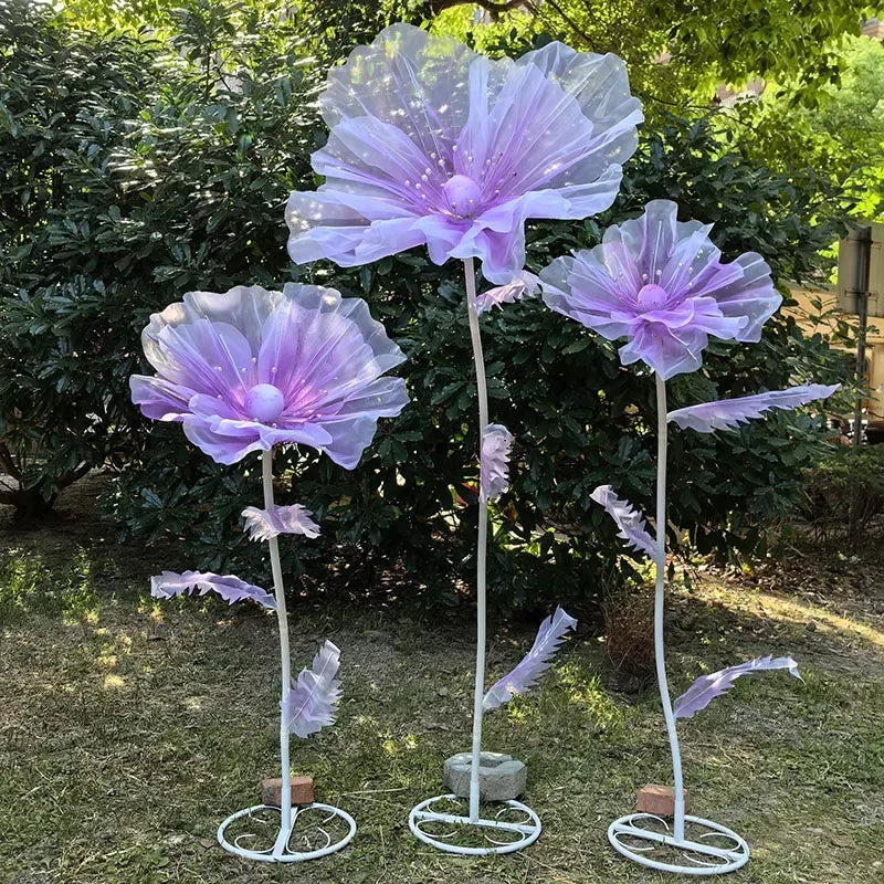 A set of three large purple and white velvet mesh flowers used as wedding or garden decorations.
