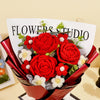 A bouquet of handcrafted red crochet roses with white accents presented in a dark red paper wrapping.