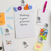 A collection of sticky notes and paper clips featuring to do, thank you, and heart designs on white and colored paper.