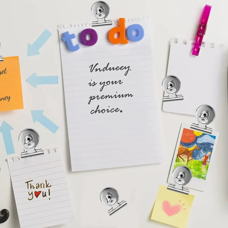 A collection of sticky notes and paper clips featuring to do, thank you, and heart designs on white and colored paper.