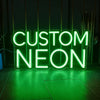 A glowing green neon sign spelling out CUSTOM NEON on a dark surface.