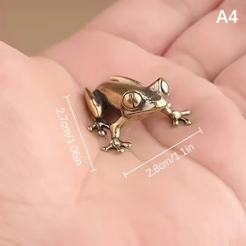 A vintage brass frog statue ornament resting on a person's hand.