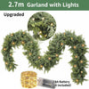 Green cedar garland with lights displayed in an arch shape, next to a AA battery.