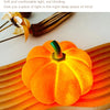 An orange decorative LED pumpkin night light resting on a wooden surface.