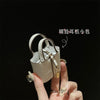 A hand holds a beige mini handbag with a gold wrist strap against a black background.