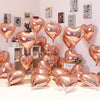 A collection of gold heart foil balloons displayed against a white wall and shelving unit.
