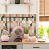 A pink and green peel-and-stick vinyl tile backsplash is displayed above a kitchen countertop.