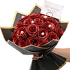 A bouquet of deep red glitter roses with white pearl accents presented in a black paper holder.