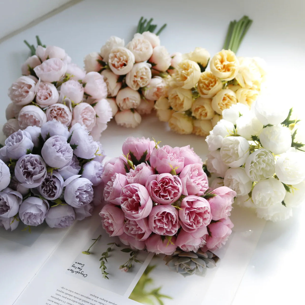 A bouquet of artificial pink peony silk flowers in various shades of pink and cream.