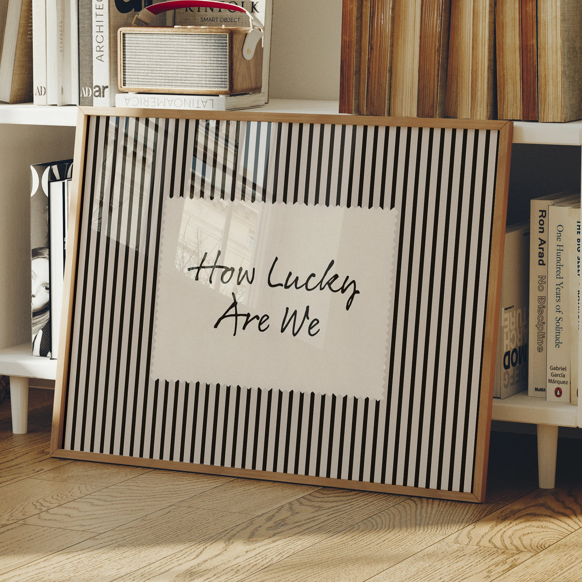 A framed canvas print with black and white vertical stripes featuring the text How Lucky Are We